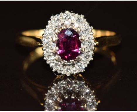 An 18ct gold ring set with an oval cut ruby of approximately 0.5ct surrounded by diamonds, 4.4g, size Q