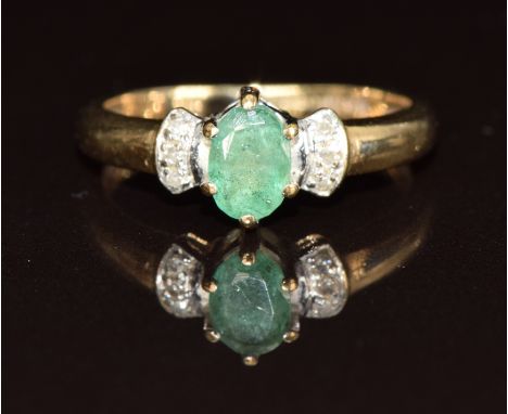 A 9ct gold ring set with an oval cut emerald and six diamonds, 1.7g, size I