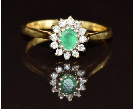 An 18ct gold ring set with an oval cut emerald surrounded by diamonds, 3.2g, size L