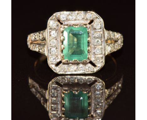 A 9ct gold ring set with an emerald cut emerald of approximately 1ct surrounded by diamonds, 3.2g, size L