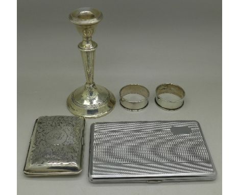 A silver cigarette case and two silver napkin rings, 66g, a silver candlestick, weighted and a chrome cigarette case