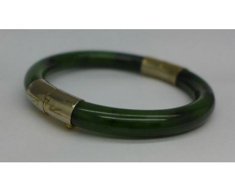 A green hardstone bangle with gilt metal mounts