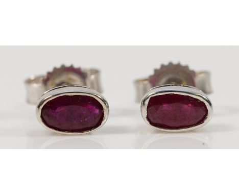 A pair of 9ct white gold ruby earrings with scroll backs, 0.6g