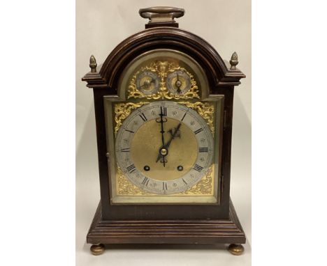 An oak bracket clock on brass supports. Est. £50 - £80.