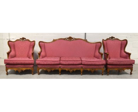 A reproduction walnut sofa in the French style, carved curved back rail and carved pelmet to base on cabriole legs, upholster