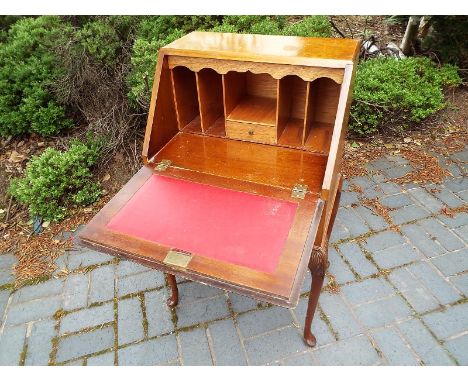 A lady's small writing  bureau, the slope front resting on manual lopers to reveal a pigeon hole fitted interior above  a sin
