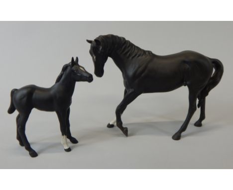 A Beswick matt black glazed ceramic horse, with one white foot, 17cm high and a matching foal