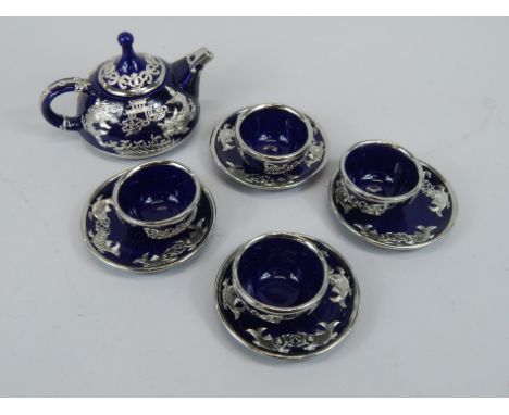 A modern Oriental tea or coffee set, comprising teapot, four cups and saucers, each with white coloured metal overlay, in a f