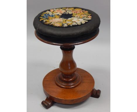 A Victorian mahogany revolving piano stool, the padded top inset with a woolwork floral panel, on splayed feet, the top 33cm 