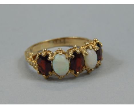 A ladies opal and garnet dress ring, on a highly elaborate shank, yellow metal marked .9 .375, 4g all in