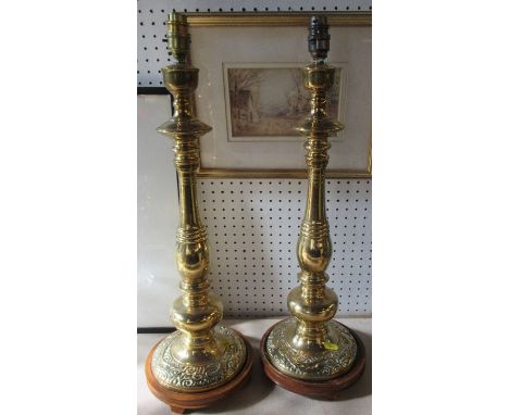 A pair of brass lamp bases, with multi knop stems, and the bases decorated with dragons, on wooden bases, height 24ins