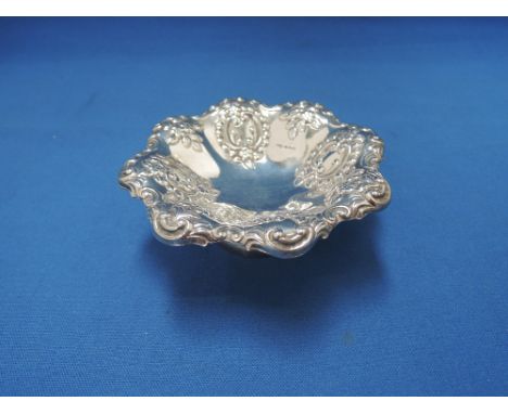 A small silver trinket dish on a raised pedestal foot having scroll and floral repousse decoration, Sheffield 1971, James Dix
