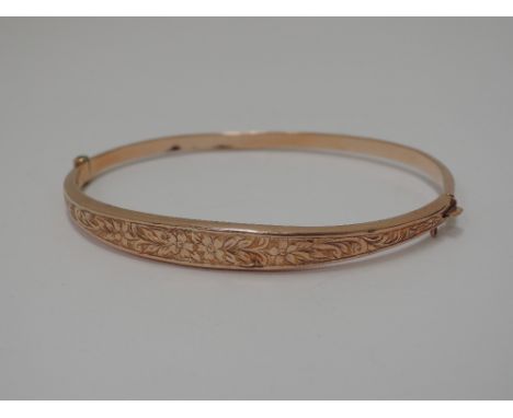 A vintage 9ct gold hinged bangle having foliate engraved decoration