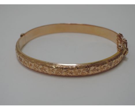 A 9ct gold hinged bangle having foliate engraved decoration