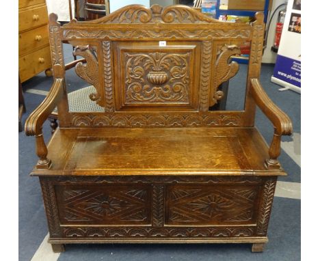 A carved oak Monks Bench, width 102cm.