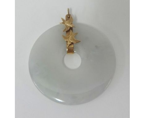 A jade disc pendant of white mottled colour, untested, with a gold mount set with two love birds, diameter 47 mm.
