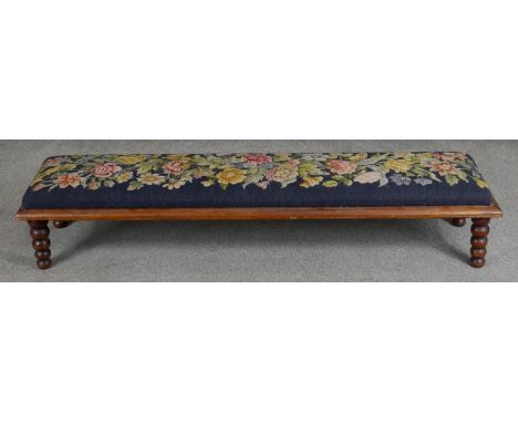 A Victorian mahogany hearth stool in floral tapestry upholstery on bobbin turned supports. H.20 L.107 D.27cm 