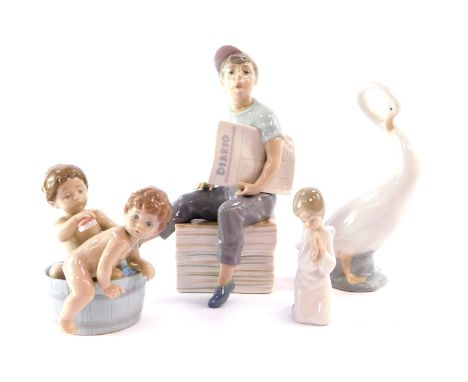 A Lladro porcelain figure modelled as two children in a bathtub, together with a Nao porcelain figure of a newspaper boy, a g