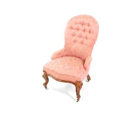 A Victorian walnut spoon back nursing chair, upholstered in button back pink floral fabric, raised on cabriole legs, on casto