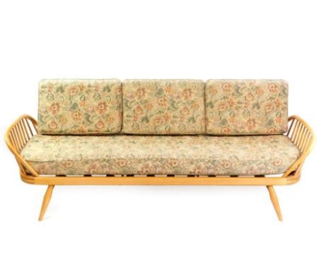 An Ercol light elm and beech three seater studio couch, with loose floral pattern cushions, raised on turned legs, 200cm wide