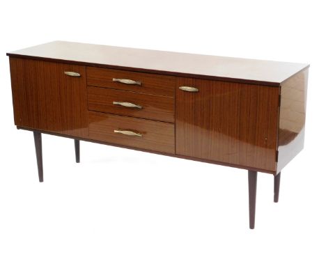 A Schreiber vintage hi gloss teak sideboard, with three central drawers, flanked by two cupboard doors, raised on turned legs