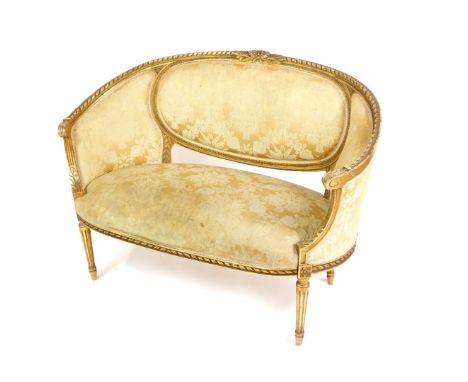 A late Victorian gilt wood two seater sofa in the French taste, upholstered in gold floral damask, raised on fluted legs, 128