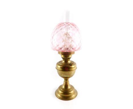 An early 20thC brass oil lamp, with a glass chimney and pink honeycomb glass shade, 53cm H.
