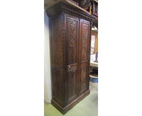 A 19th century carved oak side cupboard, floorstanding and enclosed by a pair of full length twin panelled doors, with carved