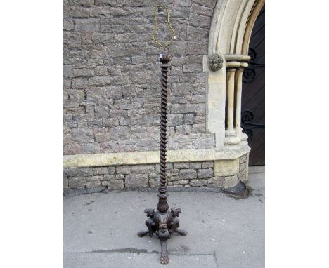 A standard lamp with spiral twist column and carved stylised dragon supports with paw feet