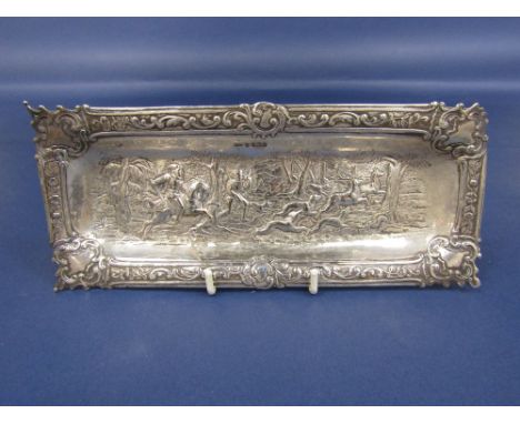 Late 19th century import silver pin tray, embossed with a hunting scene, with hounds and a stag, within raised scrolled borde