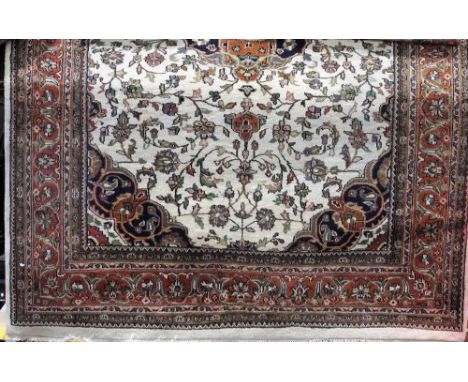 A heavy wool carpet in the Persian style, the white ground with central medallion, with abstract floral detail, set within wi