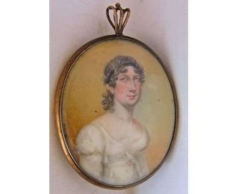 An early 19th century miniature portrait of oval form showing a woman in white dress, in circular gilt frame with a lock of h