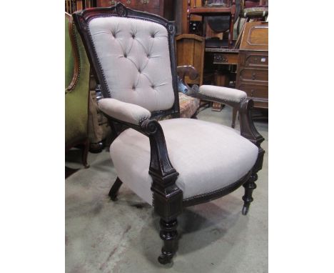 A late Victorian drawing room chair with linen upholstered seat and button back within a carved and moulded frame raised on t