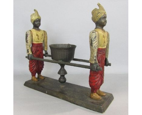 Novelty cast iron candlestick in the form of two blackamoors carrying a sedan carriage, 26cm long