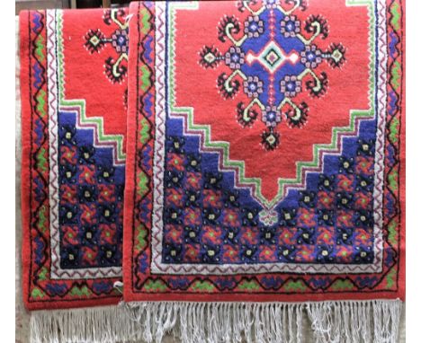 A pair of small wool rugs with red medallion centre, the larger field in a blue colourway with geometric detail, 160 x 85cm (