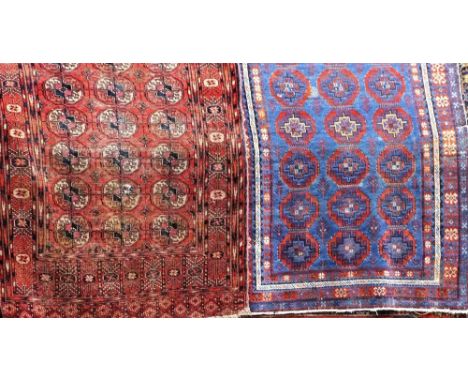 An Afghan red ground wool rug with multi medallion centre within running borders, together with a further blue ground eastern