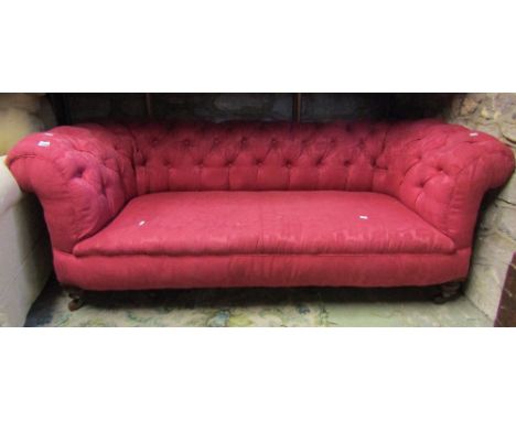 A Victorian two/three seat Chesterfield sofa with plum ground floral patterned upholstery and button back, raised on squat tu