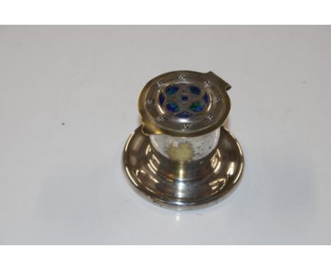 An Arts &amp; Crafts style silver plated inkwell with enamel roundel to the lid and pottery liner 