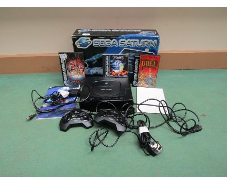 A boxed Sega Saturn computer game console with three games