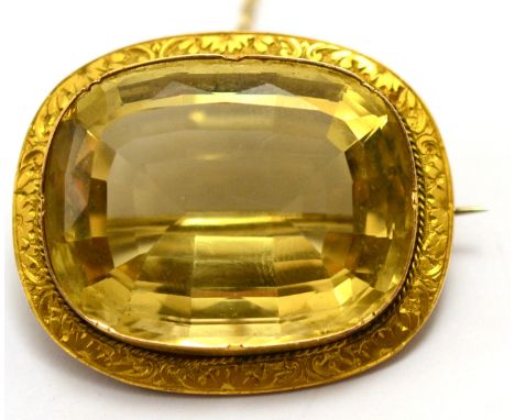 A citrine brooch, the light greenish yellow cushion mixed cut citrine in a crimped setting within a foliate chased frame, mea