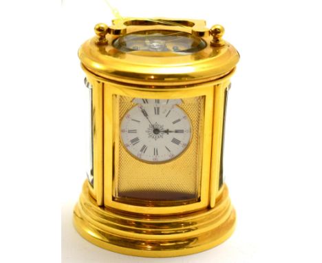 A brass miniature carriage timepiece, circa 1900, oval shaped case with glazed bevelled panels and a carrying handle, enamel 