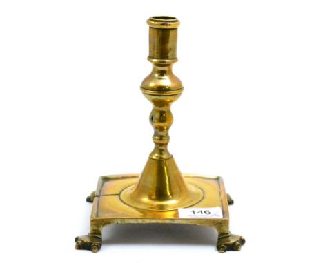 A late 17th/18th century brass candlestick, probably Spanish, the knopped stem raised on a square platform base with moulded 