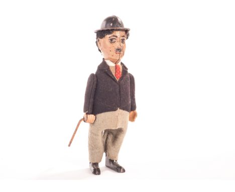 A Schuco Charlie Chaplin tinplate clockwork Figure, with tinplate face, feet and hat, black felt jacket and grey felt trouser