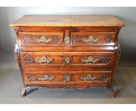An 18th Century French Oak Commode, the moulded top above two short and two long drawers with brass handles and escutcheons, 