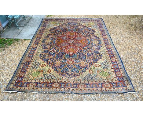 A North West Persian Woollen Carpet with a central medallion within an all-over design upon an iron red, blue and cream groun