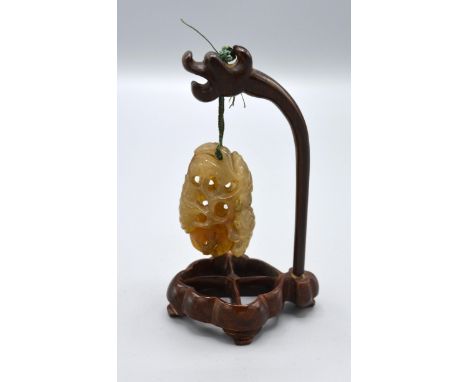 A 19th Century Jade Carving of Pierced Form with Hardwood Stand, the carving 5cm long, the stand 11cm high 