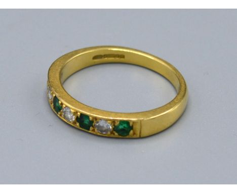 An 18ct. Gold Emerald and Diamond Band Ring set four emeralds and three diamonds, ring size N, 3.6 gms. 