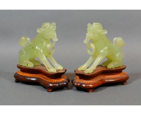 A Pair of Chinese Jade Models in the form of temple dogs, each with a hardwood stand, 13 tall 