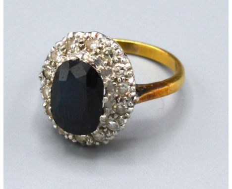 An 18ct. Gold Sapphire and Diamond Cluster Ring with an oval sapphire surrounded by diamonds within a pierced setting. 4.8 gm