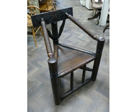Oak replica of an Anglo Saxon triangular shaped chair with bobbin turned arms and carved back panel 